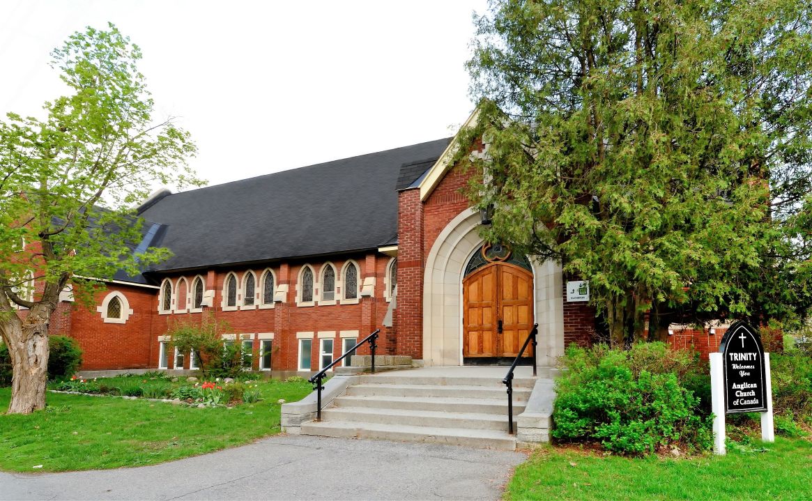 Exterior view of the red brick church with beautiful arched wooden doors.